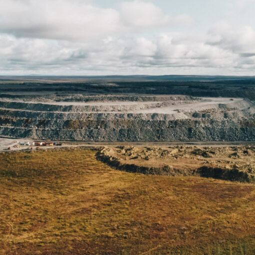 Vista panorámica de una mina a cielo abierto rodeada de paisaje natural bajo un cielo nublado.