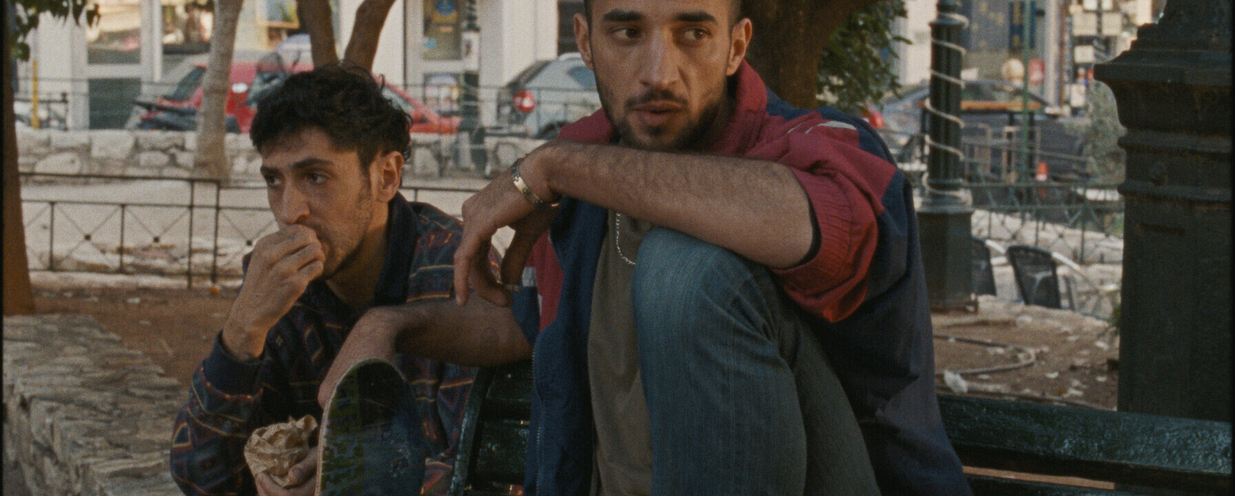 Fotograma de Hacia una tierra desconocida en el que aparecen dos hombres sentados en un banco en la calle.