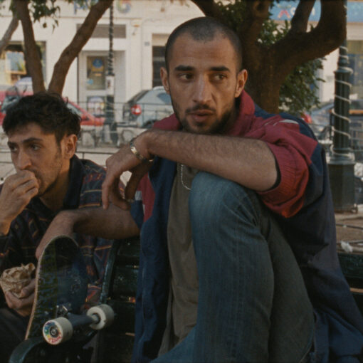 Fotograma de Hacia una tierra desconocida en el que aparecen dos hombres sentados en un banco en la calle.