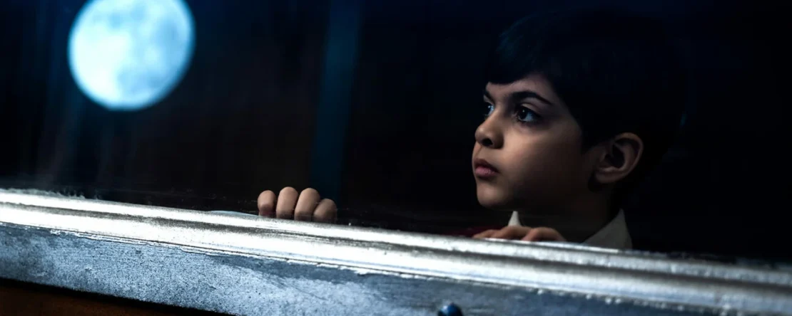 Fotograma de Expreso del Sol en el que aparece un niño mirando a través de una ventana. En el cristal, se refleja la luna.
