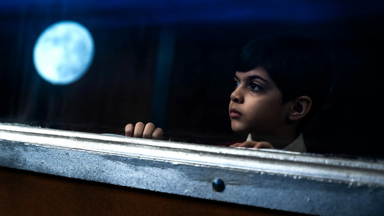 Fotograma de Expreso del Sol en el que aparece un niño mirando a través de una ventana. En el cristal, se refleja la luna.